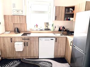 a kitchen with wooden cabinets and a white refrigerator at Apartmán Majerův dvůr in Rožnov pod Radhoštěm