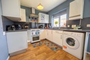 a kitchen with white cabinets and a washer and dryer at Unique By Monique Kingsholm Bungalow Parking in Gloucester