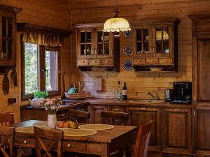 a kitchen with wooden cabinets and a table and chairs at Domek Hortensja in Zawady