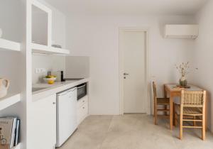a kitchen with white cabinets and a table and a dining room at Blu Dot Tinos in Dhió Kkhoriá