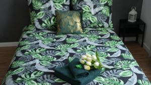 a bed with a green and white comforter with flowers on it at Pokoje Green House in Ustroń