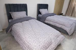 two beds sitting next to each other in a bedroom at Belgaid résidence OREVA in Oran