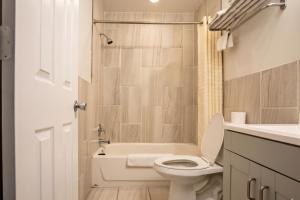 a bathroom with a toilet and a tub and a sink at Highlander Inn Cleveland Beachwood Near I-480 in North Randall +23 photos