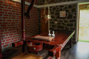 a room with a wooden table and a brick wall at Zacs Valley Resort & Wellness Retreat Kodaikanal in Kodaikānāl