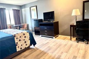 a hotel room with a bed and a flat screen tv at Highlander Inn Cleveland Beachwood Near I-480 in North Randall