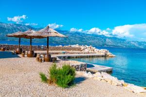 a swimming pool with umbrellas on a beach next to the water at Apartment Sankovic in Ražanac