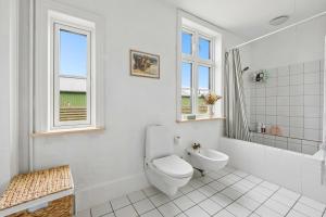 a white bathroom with a toilet and a tub and window at Lakehouse in Vester Vandet +25 photos