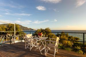 a deck with a table and chairs and the ocean at BOHALI'S HOUSE in Agios Gordios
