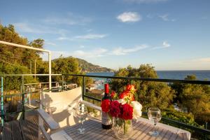 a table with flowers and wine glasses on a balcony at BOHALI'S HOUSE in Agios Gordios +25 photos