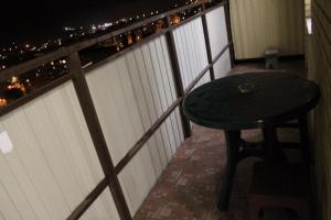 a table and stool on a balcony at night at Apartments on Chkalova in Maykop