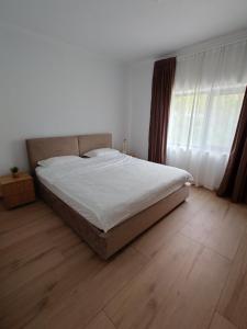 a bedroom with a bed with white sheets and a wooden floor at Casa David in Băile Govora