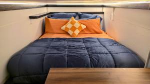 a bed in a small room with pillows and a table at Algo Azul Something Blue in Wellington