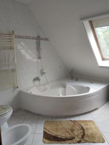a white bathroom with a tub and a toilet at Villa Panorama in Biatorbágy