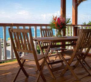a wooden table with two chairs and a vase with flowers at sunset lovers cottage in Canefield