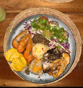 a plate of food with meat and vegetables on a table at sunset lovers cottage in Canefield