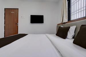 a large white bed in a room with a television at Hotel O Shree Lodging in Aurangabad