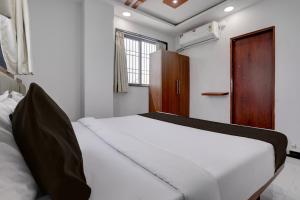 a bedroom with a white bed and a wooden door at Hotel O Shree Lodging in Aurangabad