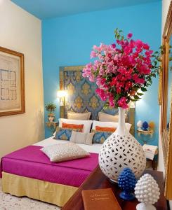 a vase with pink flowers on a table in a bedroom at Casa d'Artista con Terrazza Panoramica nel Borgo" Ajman house in Sambuca di Sicilia
