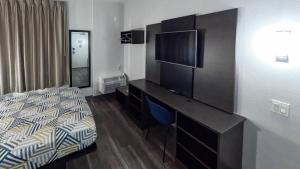 a hotel room with a bed and a desk with a television at Motel 6-Brownsville, TX in Brownsville