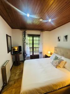 a bedroom with a large white bed with a wooden ceiling at Mountain View Guest House,Geres in Geres