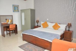 a bedroom with a bed with orange pillows and a desk at Amareen Apartments in Accra