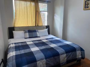 a bedroom with a bed with a checkered blanket and a window at El refugio de Lolita, tu hogar en Loja in Loja