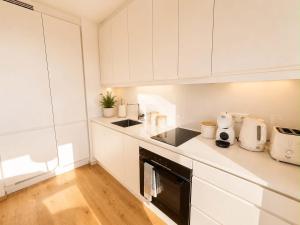 a kitchen with white cabinets and a black appliance at Sadama Apartment in Haapsalu