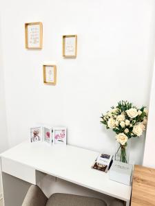 a white desk with a vase of flowers on it at Lucky apartman in Šabac