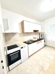 a kitchen with white cabinets and a sink at Lucky apartman in Šabac +7 photos