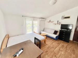 a bedroom with a bed and a table and a tv at B&V apartmani in Šušanj