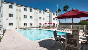 a hotel with a swimming pool with chairs and an umbrella at Studio 6-Brownsville, TX in Brownsville