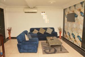 a living room with a blue couch and a table at Amareen Apartments in Accra