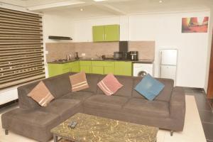 a living room with a brown couch and a kitchen at Amareen Apartments in Accra