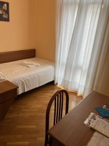 a small room with a bed and a table and a window at Hotel Saini with Air conditioning in Stresa