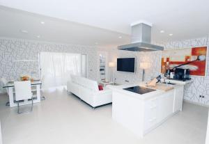 a living room with a white couch and a kitchen at Olivia Holidayhouse Maspalomas in Maspalomas