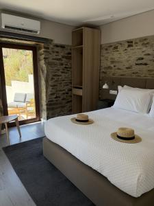 a bedroom with a bed with two hats on it at Villa Tua in Castanheiro