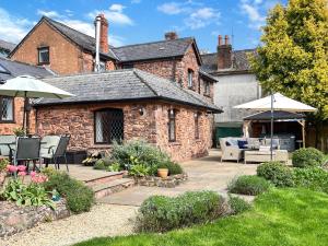 a brick house with a patio and an umbrella at Sharpe Cottage Wiveliscombe in Wiveliscombe