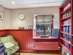 a room with a window and a chair and bookshelves at Sharpe Cottage Wiveliscombe in Wiveliscombe