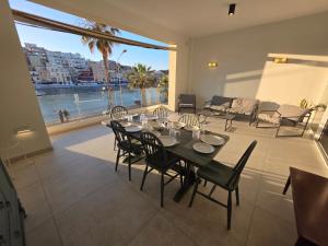 a dining table and chairs in a living room with a view at Luxury Waterfront 3BR Apartment with Large Terrace in Marsaskala