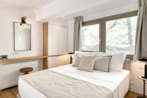 a bedroom with a large white bed with a window at Panormos Bay Suites Luxury Resort in Mikonos +97 photos