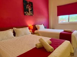 two beds in a room with red walls at Hotel Barranquilla in Campeche +33 photos