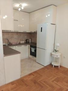 a kitchen with white cabinets and a white refrigerator at Apartman Budva in Budva +3 photos