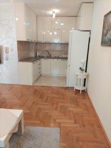 a kitchen with white cabinets and a wooden floor at Apartman Budva in Budva