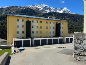 a large yellow building with doors in front of a mountain at Mountain spot in a cozy nest in Airolo