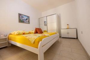 a bedroom with a bed with a yellow comforter at Apartmani Soldan in Makarska