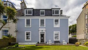 a blue house with two chairs in a yard at Williams Haven in Rothesay +10 photos