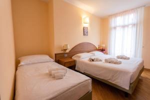two beds in a hotel room with towels on them at Hotel Saini with Air conditioning in Stresa