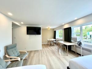 a hotel room with a bed and a tv and a table at English Bay Hotel in Vancouver