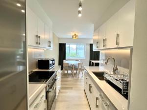 a kitchen with white cabinets and a table in it at English Bay Hotel in Vancouver