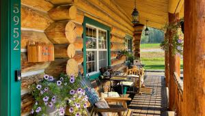 a porch of a log cabin with purple flowers at Dodge Peak Lodge in Bonners Ferry
